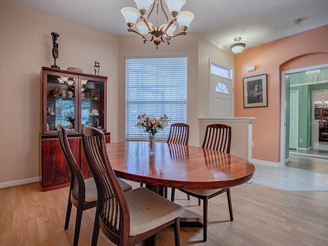 910 Eagles Lndg, Leesburg, FL 34748 - dining space with a chandelier, light wood-type flooring, baseboards, and a textured ceiling