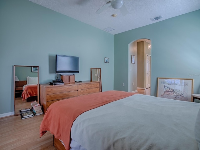 910 Eagles Lndg, Leesburg, FL 34748 - bedroom with arched walkways, light wood-style flooring, baseboards, a ceiling fan, and a textured ceiling
