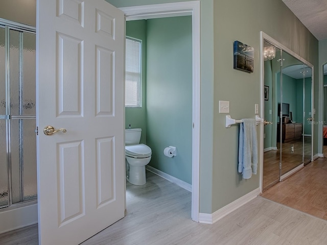 910 Eagles Lndg, Leesburg, FL 34748 - full bathroom with toilet, wood finished floors, a shower with shower door, and baseboards