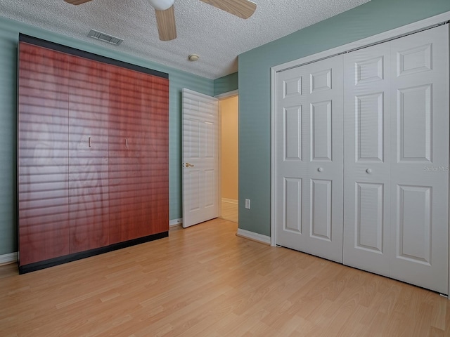 910 Eagles Lndg, Leesburg, FL 34748 - unfurnished bedroom featuring light wood-style floors, a closet, a textured ceiling, baseboards, and ceiling fan