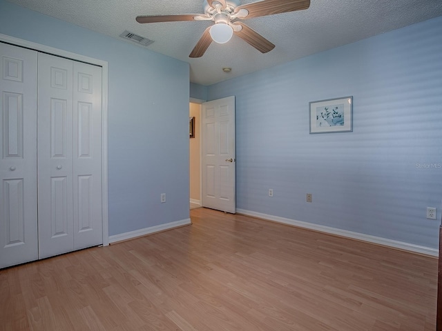 910 Eagles Lndg, Leesburg, FL 34748 - unfurnished bedroom with light wood-style floors, baseboards, a closet, a textured ceiling, and ceiling fan