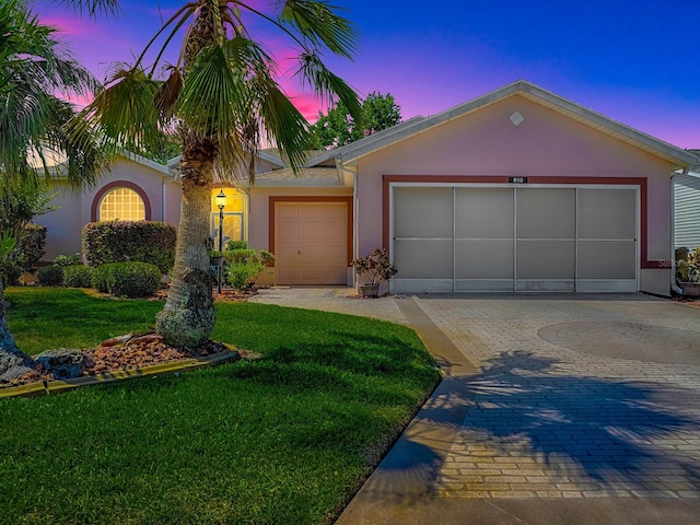 910 Eagles Lndg, Leesburg, FL 34748 - view of front of home featuring stucco siding, a yard, decorative driveway, and an attached garage