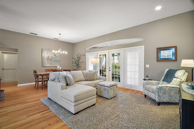 living room with french doors, visible vents, light wood-style flooring, and a notable chandelier