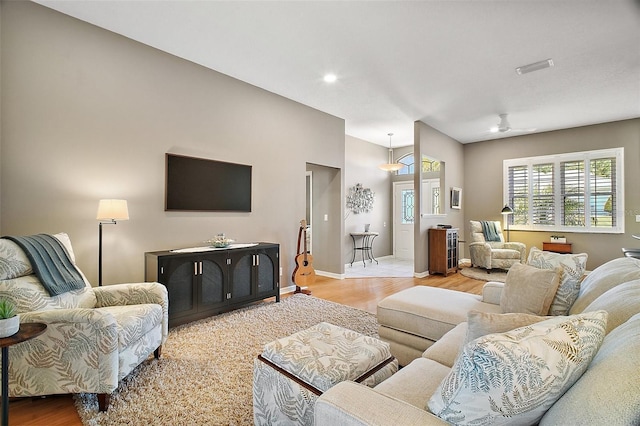 living room featuring baseboards, ceiling fan, and wood finished floors