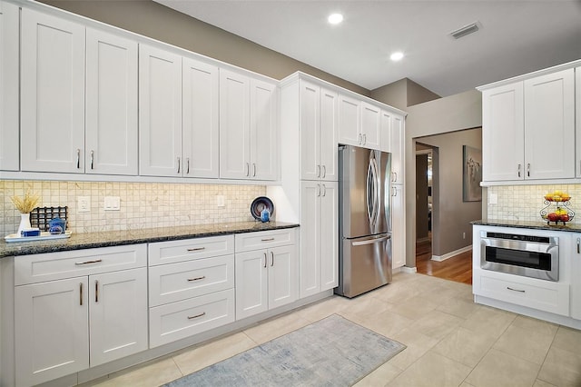 kitchen featuring visible vents, white cabinets, appliances with stainless steel finishes, and dark stone counters