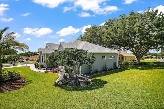 view of home's exterior featuring a yard, a shingled roof, and stucco siding