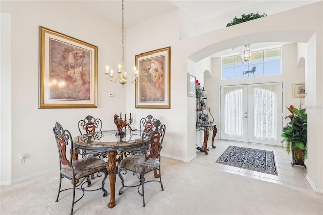 carpeted foyer with baseboards, an inviting chandelier, tile patterned floors, french doors, and arched walkways