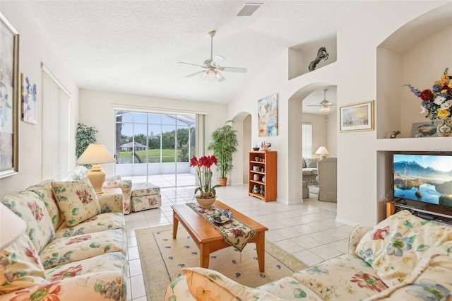 living room featuring arched walkways, light tile patterned floors, a ceiling fan, and lofted ceiling