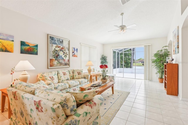 living room featuring visible vents, a ceiling fan, light tile patterned flooring, and a textured ceiling