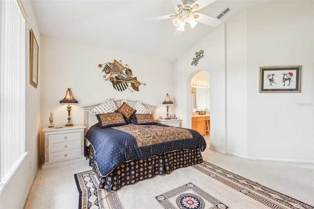 carpeted bedroom with high vaulted ceiling, ensuite bathroom, arched walkways, visible vents, and baseboards
