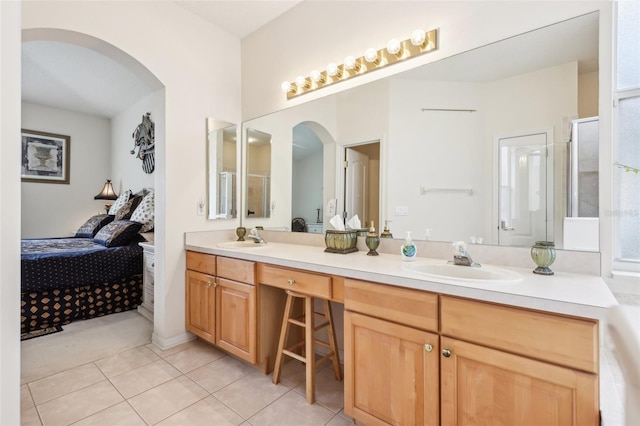 bathroom featuring a sink, tile patterned flooring, double vanity, and ensuite bath