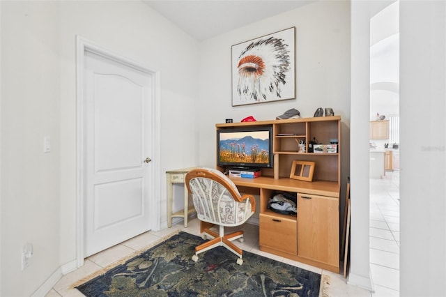 office space with arched walkways, built in study area, baseboards, and light tile patterned flooring