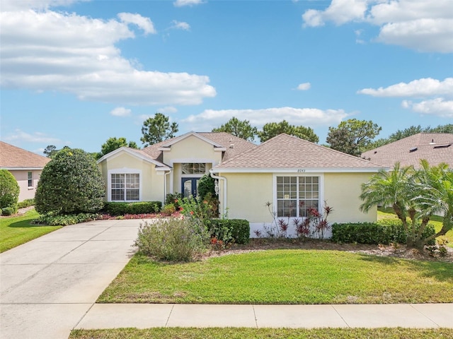 single story home featuring a front yard, stucco siding, and a shingled roof