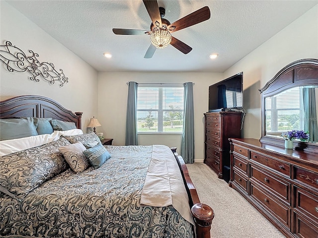 bedroom with a ceiling fan, baseboards, a textured ceiling, and light colored carpet