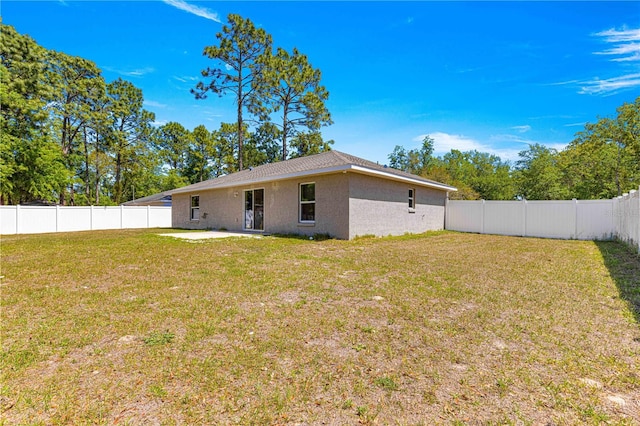 back of property with a fenced backyard, stucco siding, a patio, and a yard