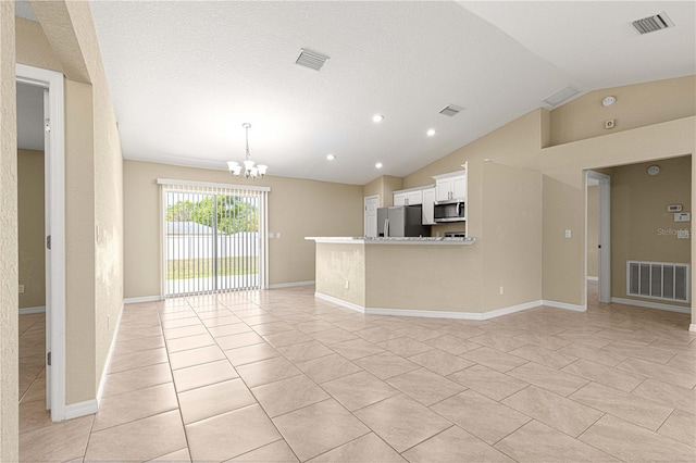 unfurnished living room featuring an inviting chandelier, baseboards, lofted ceiling, and visible vents