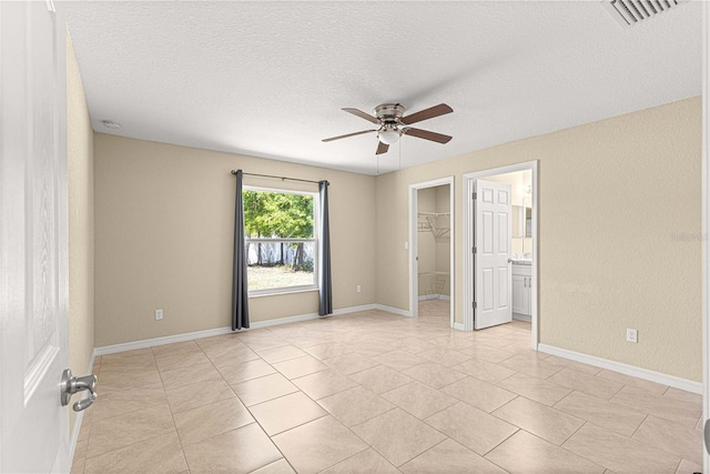 spare room with baseboards, a textured ceiling, visible vents, and a ceiling fan