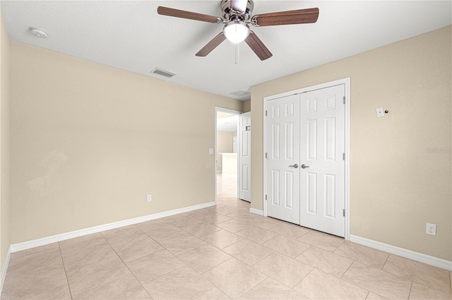 unfurnished bedroom with light tile patterned floors, baseboards, visible vents, a ceiling fan, and a closet