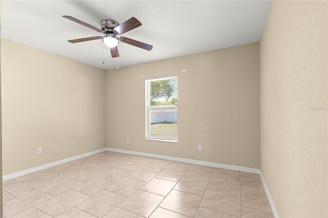 empty room with light tile patterned flooring, baseboards, and a ceiling fan