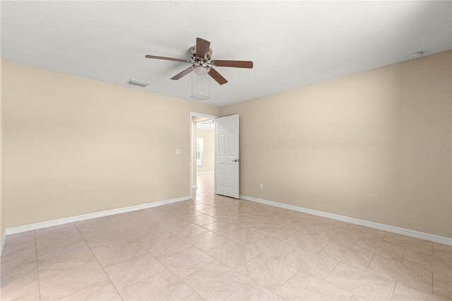 spare room with a ceiling fan, a textured ceiling, light tile patterned floors, baseboards, and visible vents