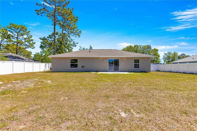back of property with a fenced backyard and a yard