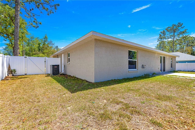 view of property exterior featuring cooling unit, a gate, stucco siding, and a yard