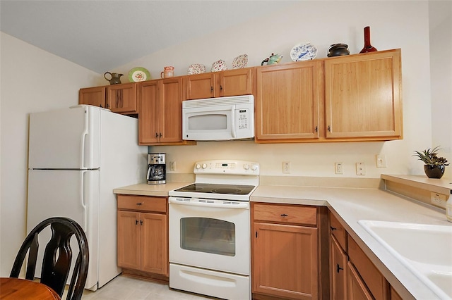 kitchen with a sink, light countertops, white appliances, and vaulted ceiling