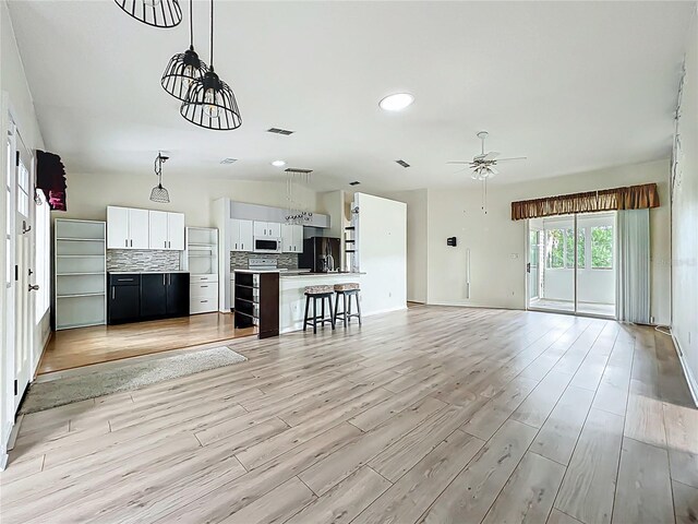 unfurnished living room with light wood finished floors, ceiling fan, and visible vents