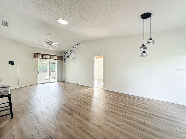unfurnished living room featuring light wood finished floors, a textured ceiling, visible vents, and a ceiling fan