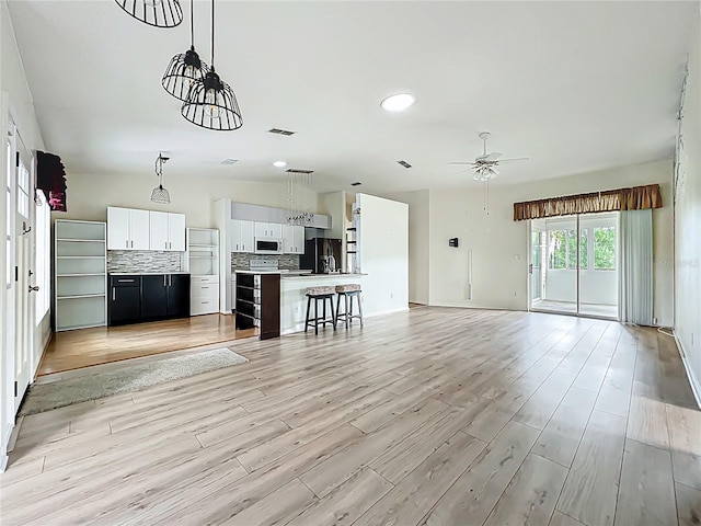 unfurnished living room with light wood finished floors, ceiling fan, and visible vents