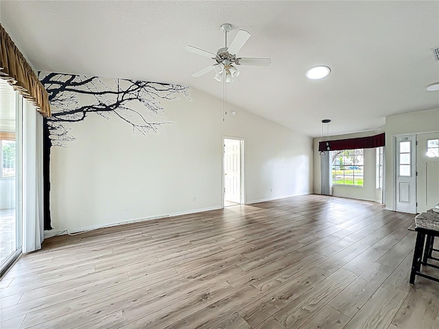 unfurnished living room with a ceiling fan, lofted ceiling, light wood-style flooring, baseboards, and visible vents