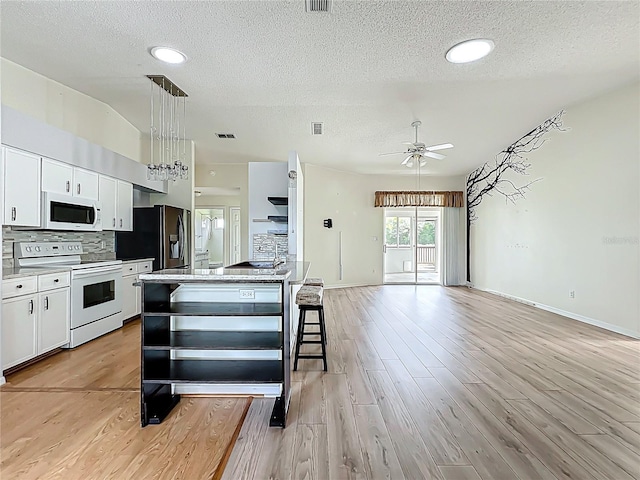 kitchen with light wood finished floors, tasteful backsplash, white appliances, visible vents, and white cabinets