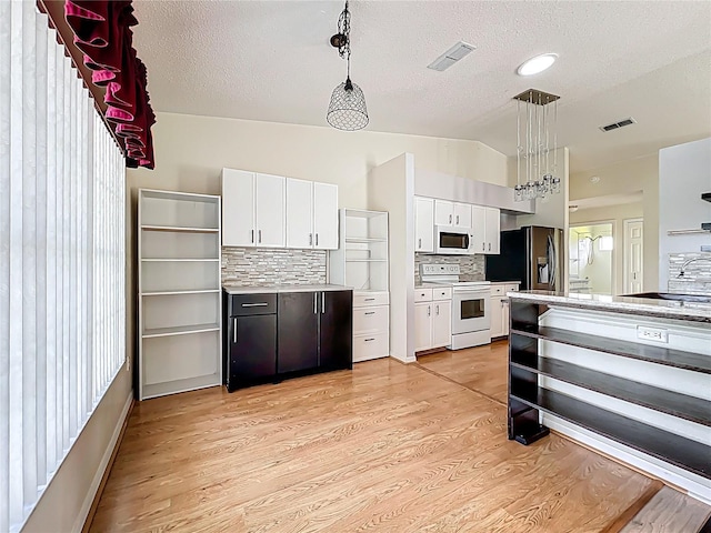 kitchen featuring light countertops, white appliances, white cabinetry, light wood-type flooring, and vaulted ceiling