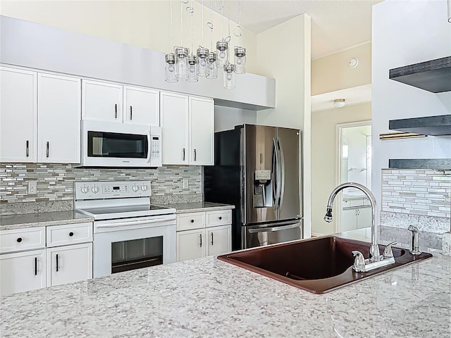 kitchen featuring decorative backsplash, white cabinetry, a sink, and white appliances