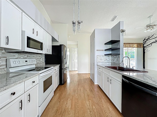 kitchen with white appliances, a sink, light wood finished floors, ceiling fan, and white cabinets