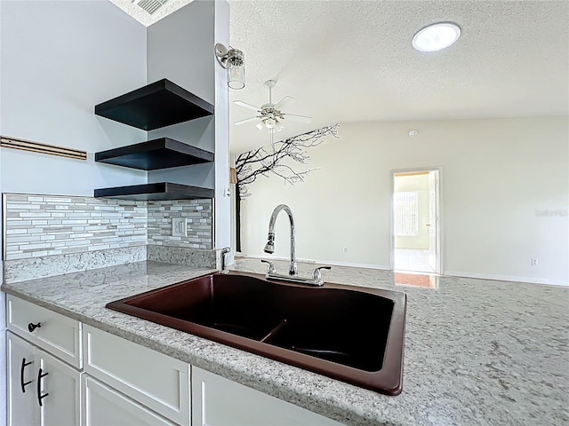 kitchen with decorative backsplash, ceiling fan, white cabinetry, a sink, and open shelves