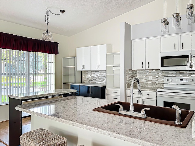 kitchen with decorative backsplash, pendant lighting, white cabinets, and vaulted ceiling