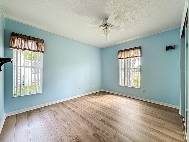 spare room featuring baseboards, a textured ceiling, wood finished floors, and a ceiling fan