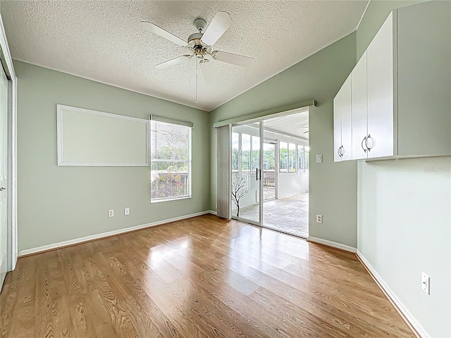 unfurnished room with a textured ceiling, baseboards, ceiling fan, wood finished floors, and lofted ceiling