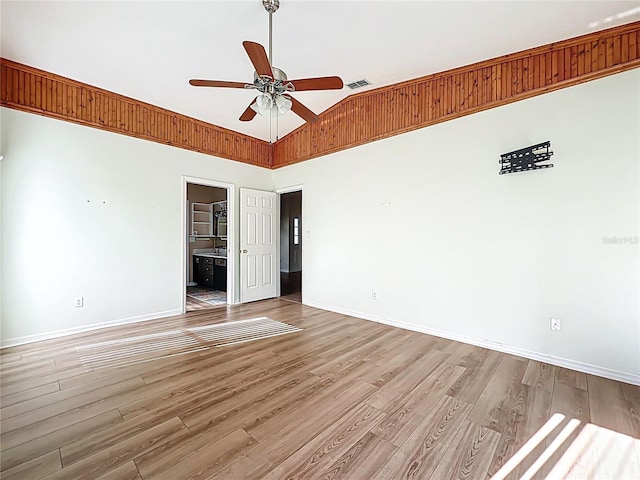 spare room featuring a ceiling fan, wood finished floors, lofted ceiling, baseboards, and visible vents
