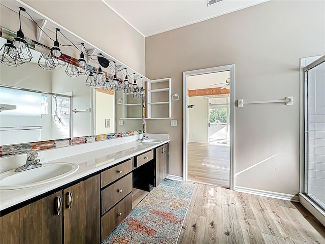 full bath featuring double vanity, wood finished floors, baseboards, and a sink