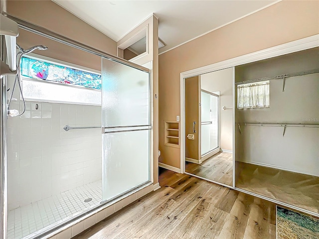 bathroom featuring wood finished floors, a stall shower, toilet, and plenty of natural light