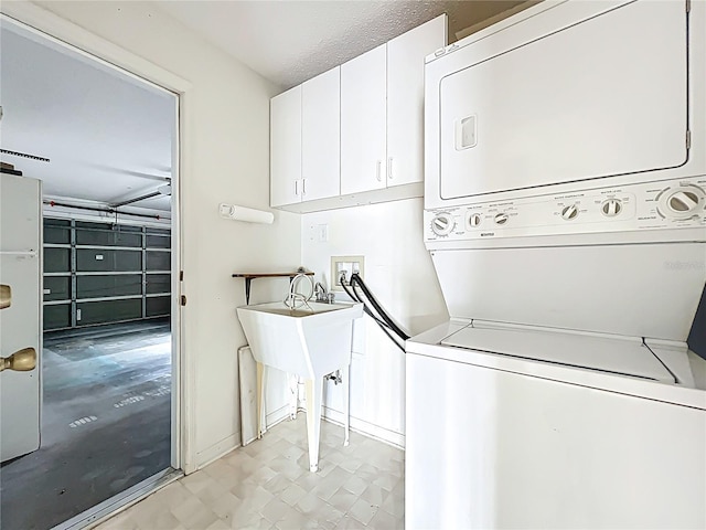 washroom with a garage, cabinet space, and stacked washing maching and dryer