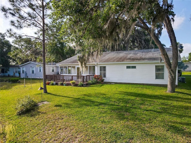 rear view of property with a lawn, a deck, and central AC