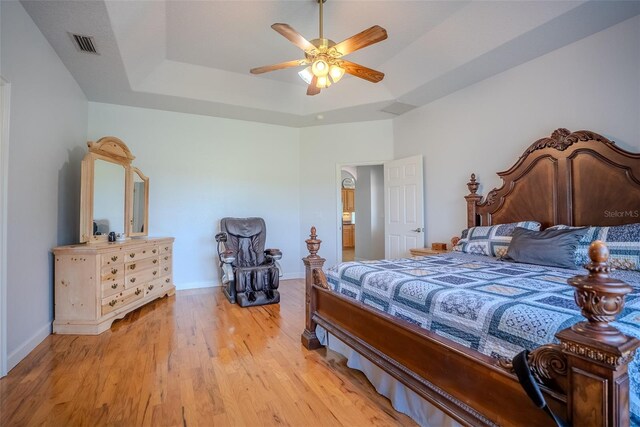15141 Farm Rd, Groveland, FL 34736 - bedroom with visible vents, baseboards, a ceiling fan, light wood-style floors, and a tray ceiling