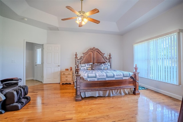 15141 Farm Rd, Groveland, FL 34736 - bedroom featuring baseboards, a tray ceiling, light wood-style floors, and ceiling fan