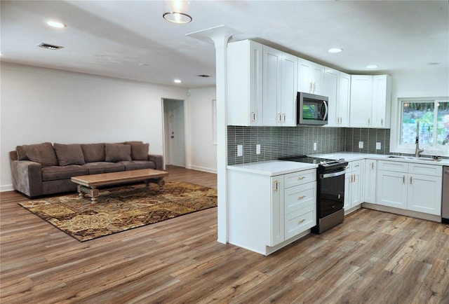 kitchen featuring stainless steel appliances, open floor plan, light wood-type flooring, and a sink