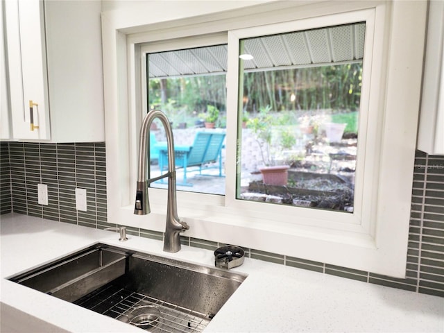 details with white cabinets, light countertops, a sink, and decorative backsplash