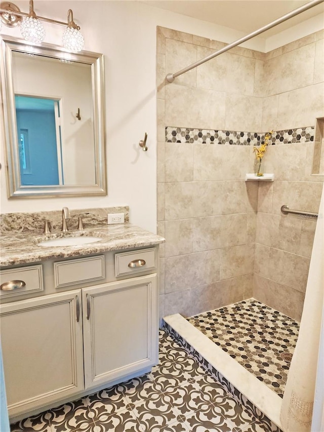 bathroom with a tile shower, vanity, and tile patterned flooring