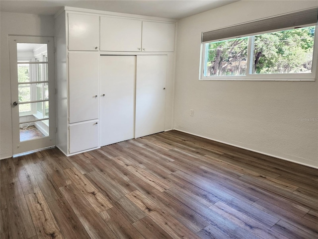 unfurnished bedroom with wood finished floors, a textured wall, and a closet